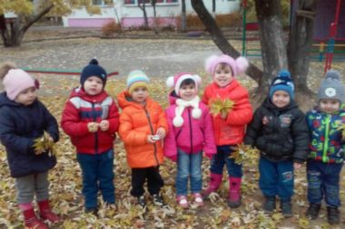 Дети стоят с осенними листьями в руках
