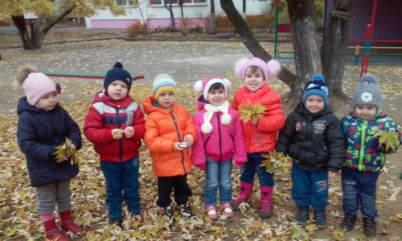 Дети стоят с осенними листьями в руках