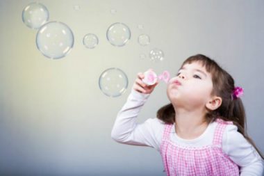 Девочка дует мыльные пузыри