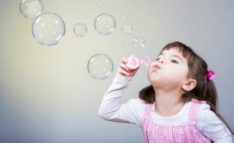 Девочка дует мыльные пузыри