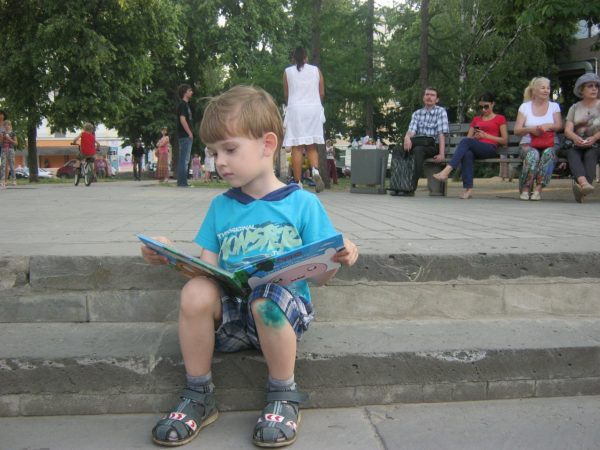 Ребёнок читает книгу на улице