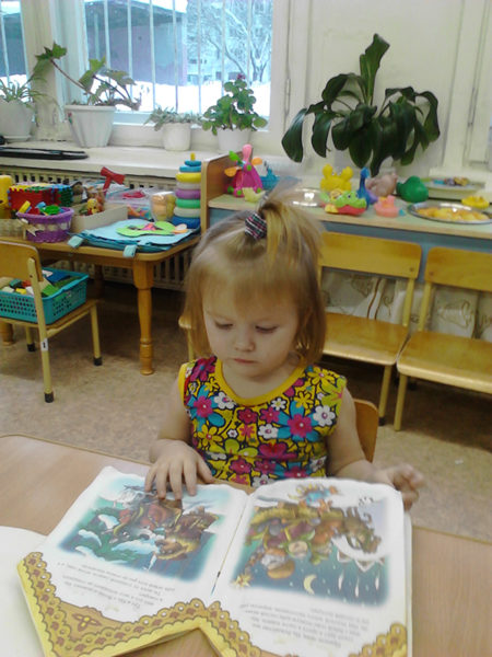 Девочка рассматривает книгу в детском саду