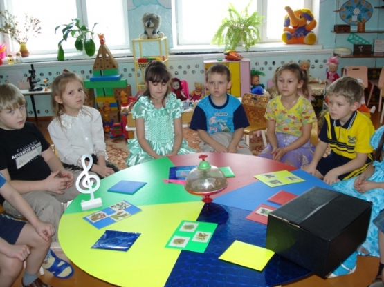 Дети сидят за круглым столом, на котором разложены дидактические материалы