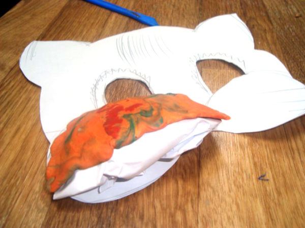 На бумажной маске лежит скомканный лист бумаги с нанесённым на него слоем пластилина