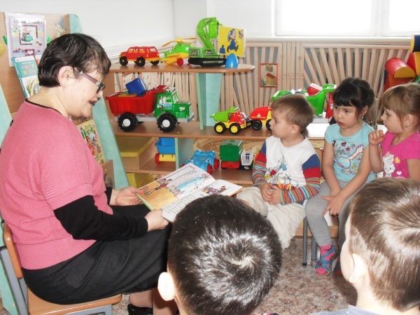Воспитатель читает книгу в младшей группе