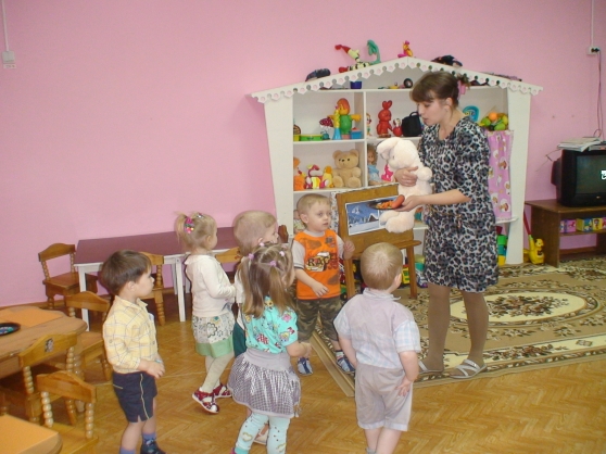 Воспитатель показывает детям игрушечного зайца