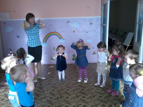 Дети и воспитательница, стоя в кругу, делают зарядку