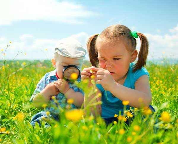 Мальчик и девочка рассматривают цветы на лугу