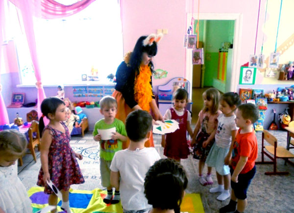 Педгог в костюме лисички предлагает детям собрать геометрический ковёр