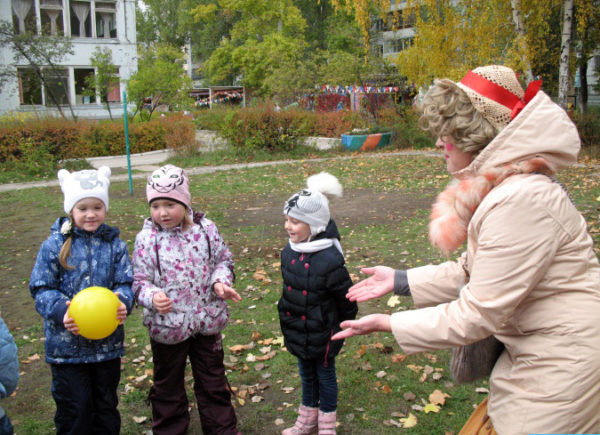 Дети и воспитатель играют с мячом на улице