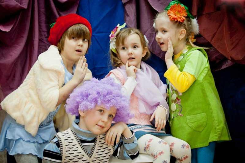 Три девочки и мальчик в сиреневом парике в актёрских образах