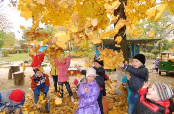 Дети подбрасывают опавшие листья