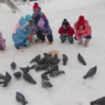 Дети кормят голубей на снегу