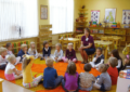 Дети с воспитательницей сидят в кругу на оранжевом коврике