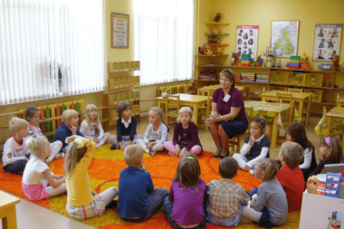 Дети с воспитательницей сидят в кругу на оранжевом коврике