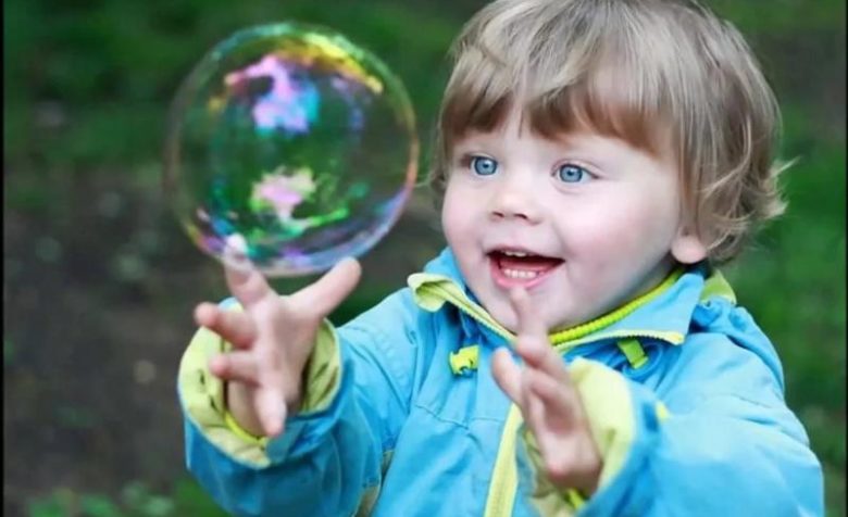 ребёнок рассматривает мыльный пузырь