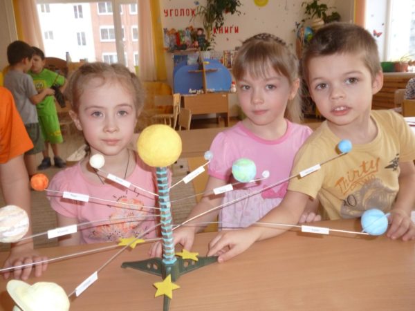 Трое детей стоят рядом с макетом Солнечной системы