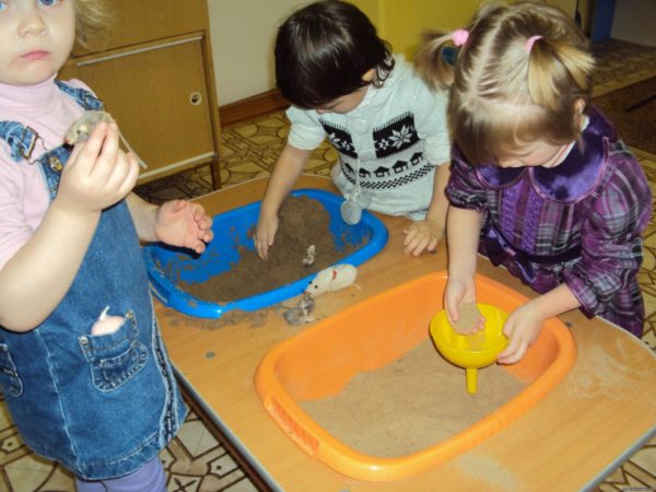 Дети изучают свойства сухого и сырого песка в центре экспериментирования
