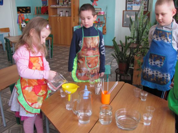 Два мальчика и девочка проводят эксперимент с водой