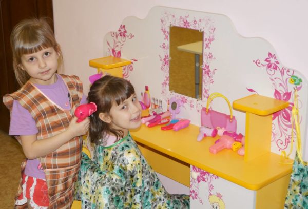 Две девочки играют в парикмахерскую