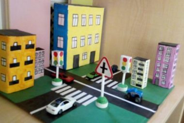 Макет улицы с перекрёстком, дорожными знаками, светофором и белой игрушечной машинкой