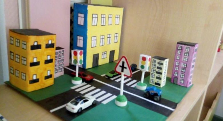Макет улицы с перекрёстком, дорожными знаками, светофором и белой игрушечной машинкой