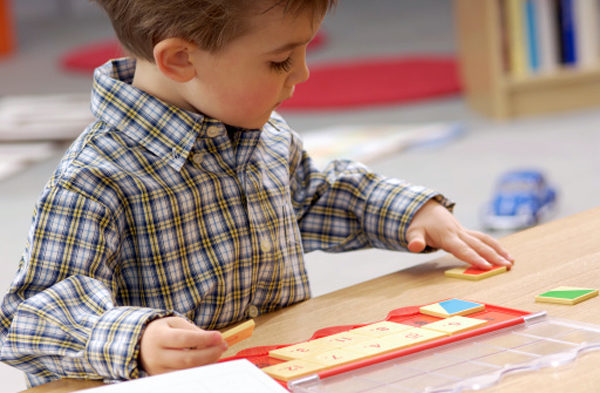 Мальчик складывает мозаику с цифрами на квадратах