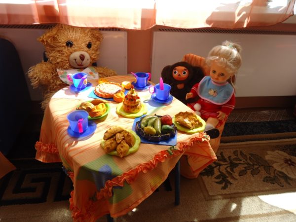 Кукла и игрушки за обеденным столом
