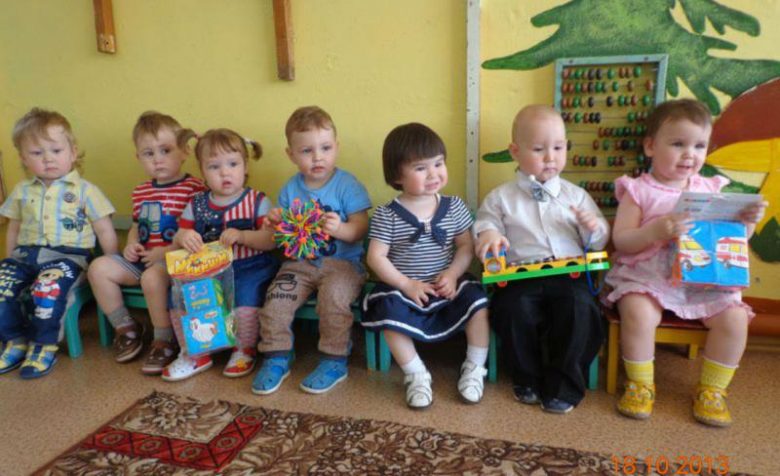 Семеро детей сидят на скамейке, у двух девочек в руках кубики-мякиши, у мальчика мозаика-фонарик