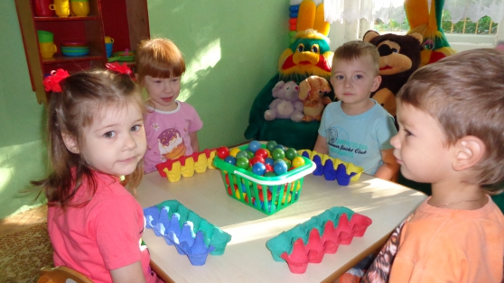 Четверо детей сортируют цветные шарики в картонные блоки для яиц подходящего оттенка