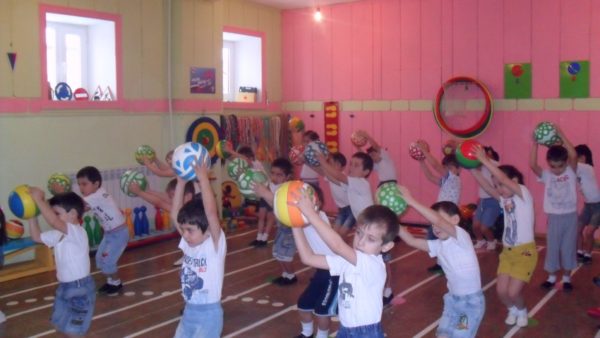 Группа детей выполняет упражнение с мячами