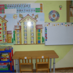 На стене размещены два домика с буквами, слева — стеллаж с играми