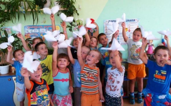 Дети с бумажными фигурками голубей в руках