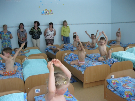 Дети в кроватках сидят, подняв руки вверх