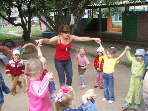 Педагог делает с детьми спортивное упражнение на улице