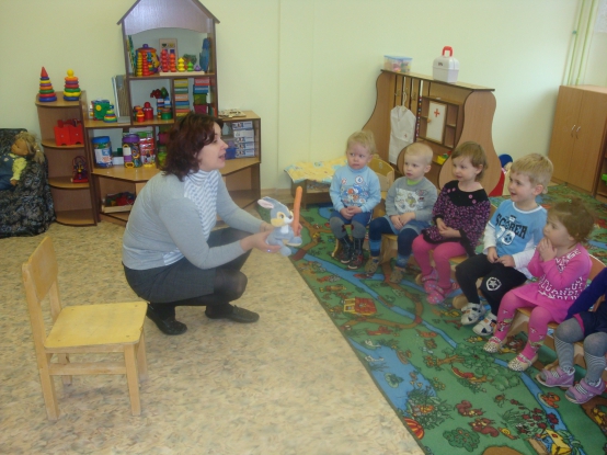 Воспитательница показывает детям игрушку-зайца