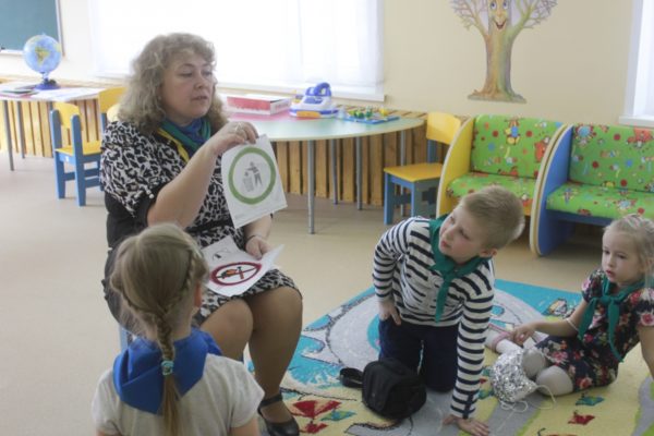 Воспитательница показывает детям экологические знаки