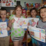 Четверо детей держат рисунки