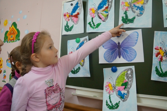Девочка указывает на картинку с бабочкой, размещённую на доске