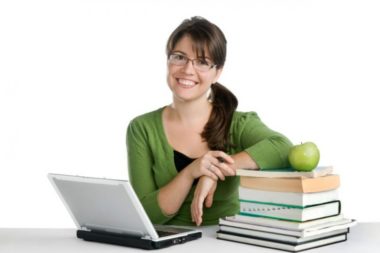 Девушка за ноутбуком со стопкой книг и яблоком
