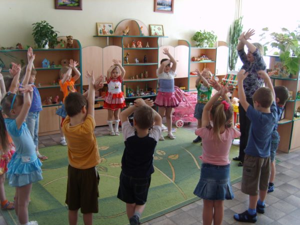 Дети и педагог стоят в кругу с поднятыми вверх руками