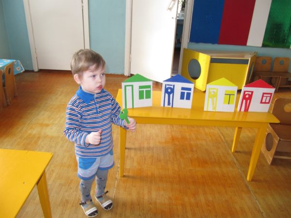 Мальчик держит в руке ключ из зелёного картона, рядом на столе стоят разноцветные домики