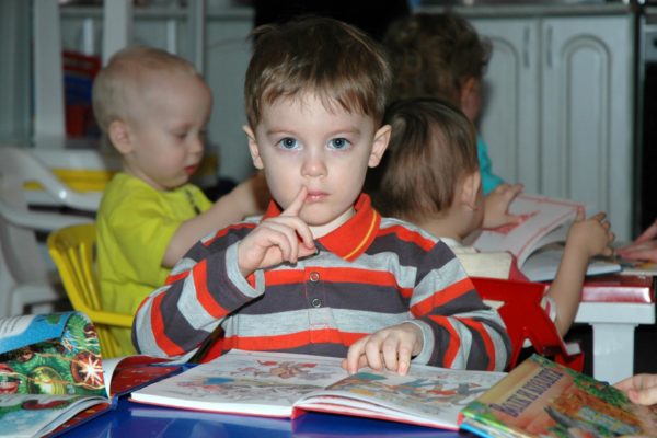 Мальчик сидит перед раскрытой книгой