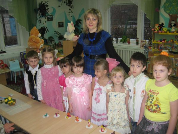 Педагог и группа детей стоят возле стола, на нём лежат вылепленные из пластилина герои сказок
