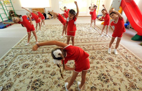 Дети в красной спортивной форме делают зарядку