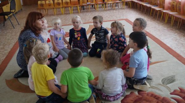 Воспитатель и дети сидят на ковре в кругу