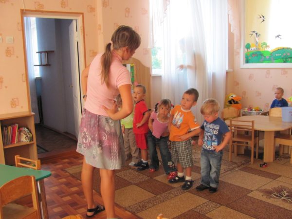 Малыши и педагог делают зарядку в помещении группы