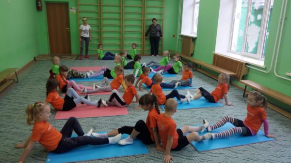 Дети выполняют упражнение на ковриках в спортивном зале