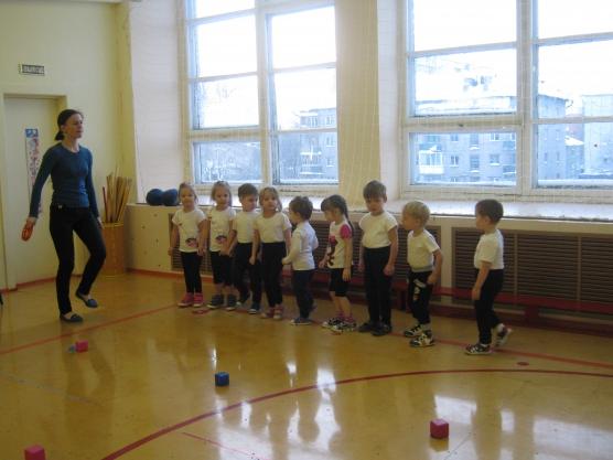 Педагог показывает упражнение детям, стоящим в шеренге