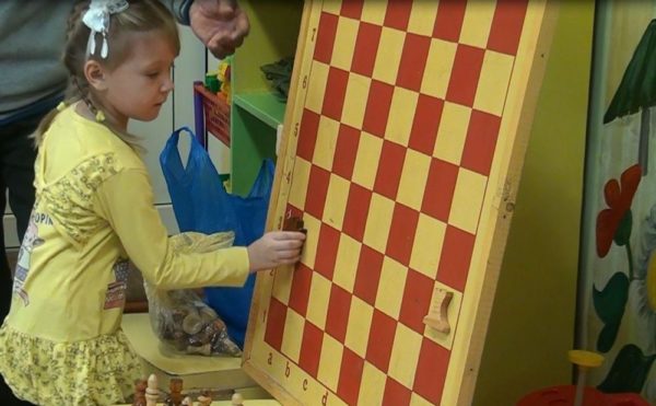 Девочка играет с магнитной доской, к которой крепятся шахматы